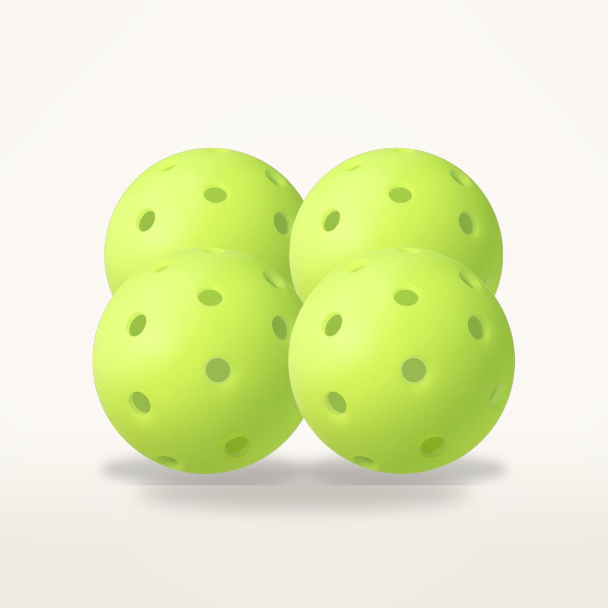 Quatre balles de pickleball d'extérieur vert fluo percées de petits trous, groupées sur fond neutre